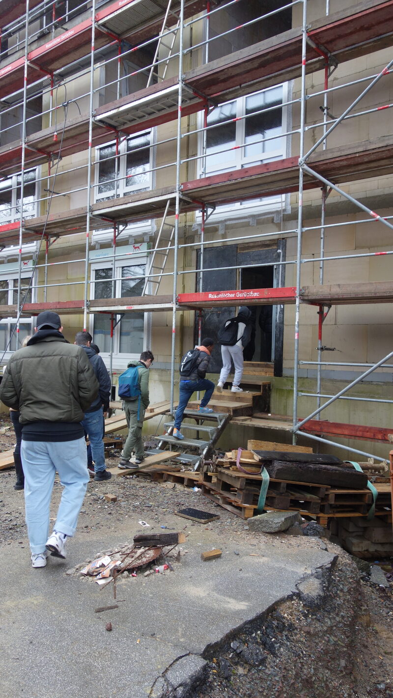 Eine Gruppe Jugendliche geht in eine Baustelle-Gebäude rein