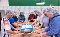 Teilnehmenden bereiten Brötchen an einem Großen Tisch in der Backstube