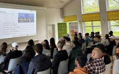 Studenten sitzen im Seminarsaal vor einer Powerpoint-Präsentation