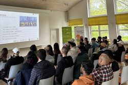 Studenten sitzen im Seminarsaal vor einer Powerpoint-Präsentation